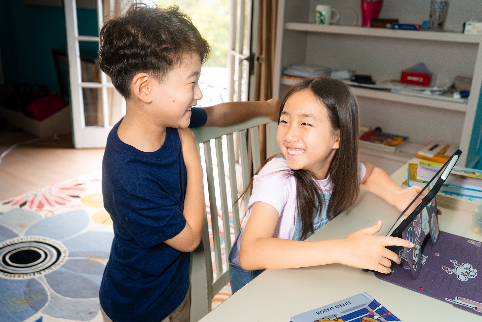 Two kids laughing during a live Nao Now lesson on a tablet