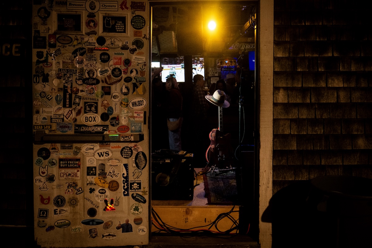 The backstage door at the Woodshed in Brewster MA. Josh Ayala will play. His signature hat sits on top of his guitar on the stage, we see it from outside.