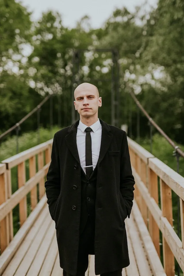 a man in a suit and tie standing on a bridge