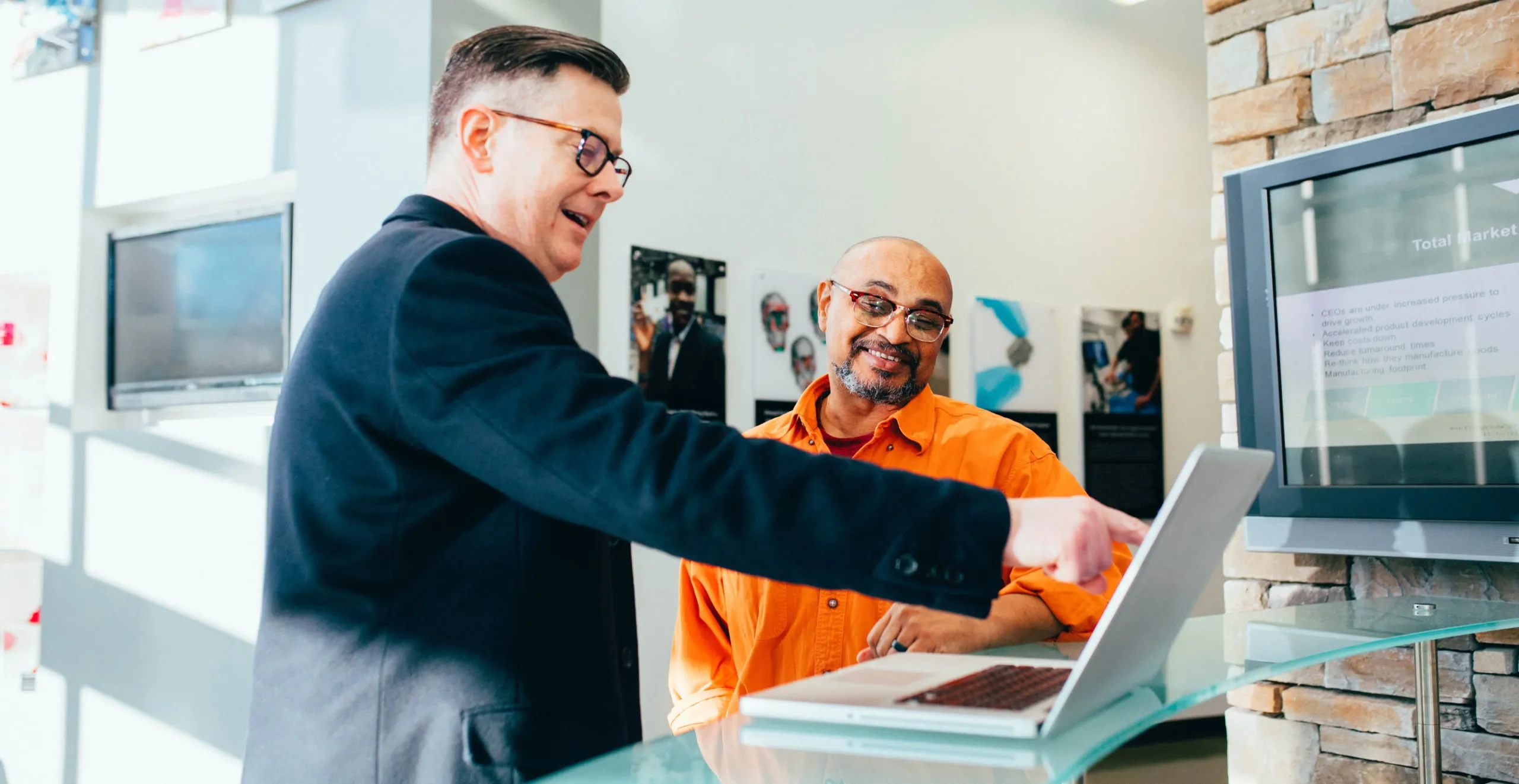 two men shaking hands over a laptop computer