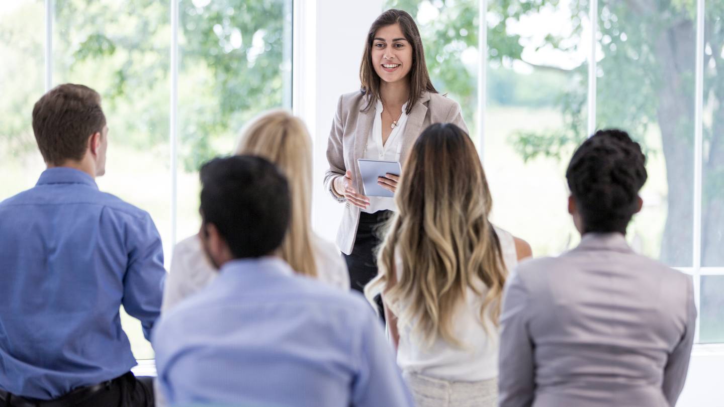 business professional giving a presentation in front of a small group of people