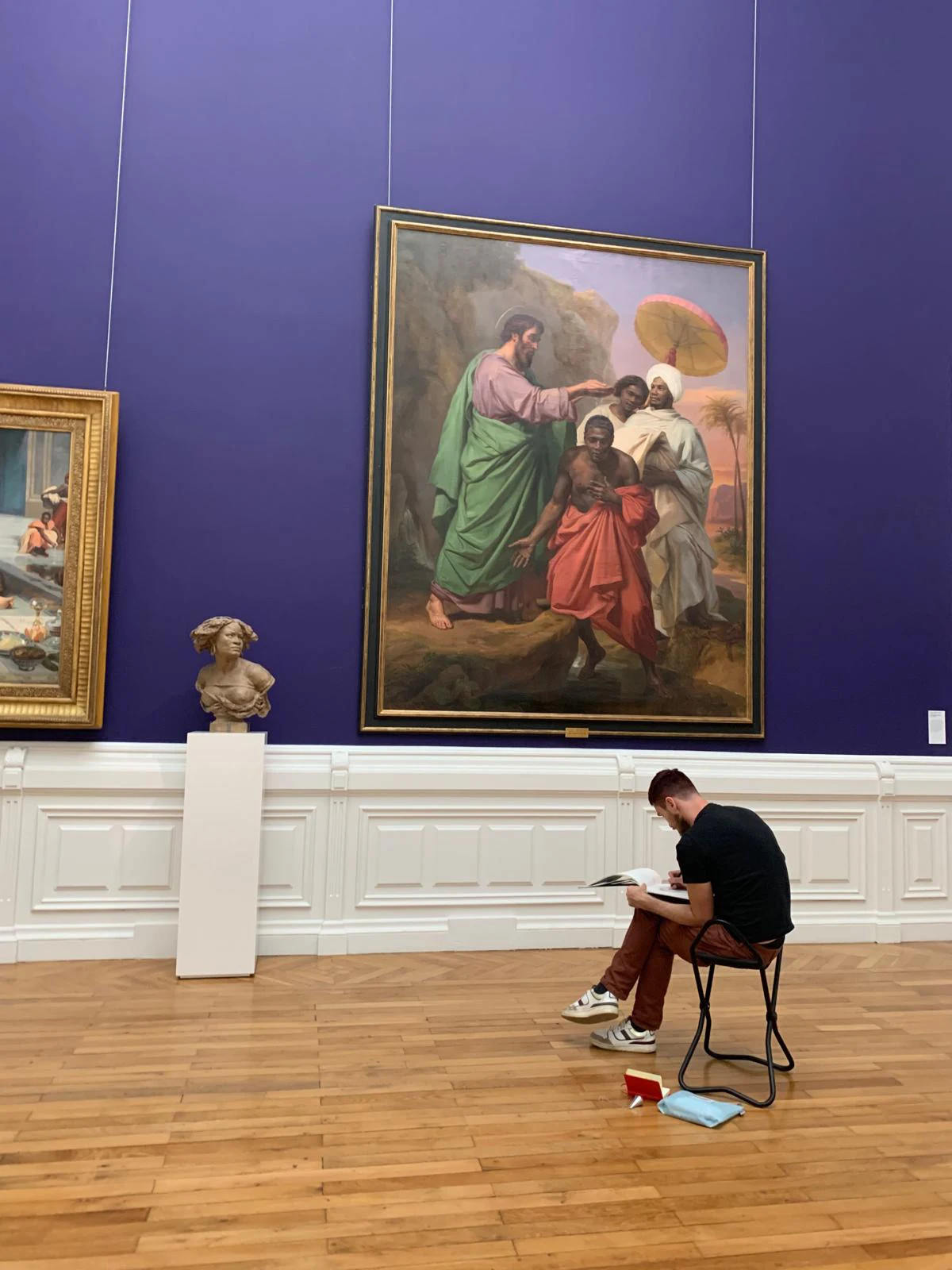 cours au musée d'art de nantes. On voit quelqu'un qui dessine devant des oeuvres d'art, assis sur une petite chaise pliante. Il nous tourne le dos et bien qu'on voit de grande peinture, on comprend qu'il essaye de reproduire le buste sculpté devant lui.