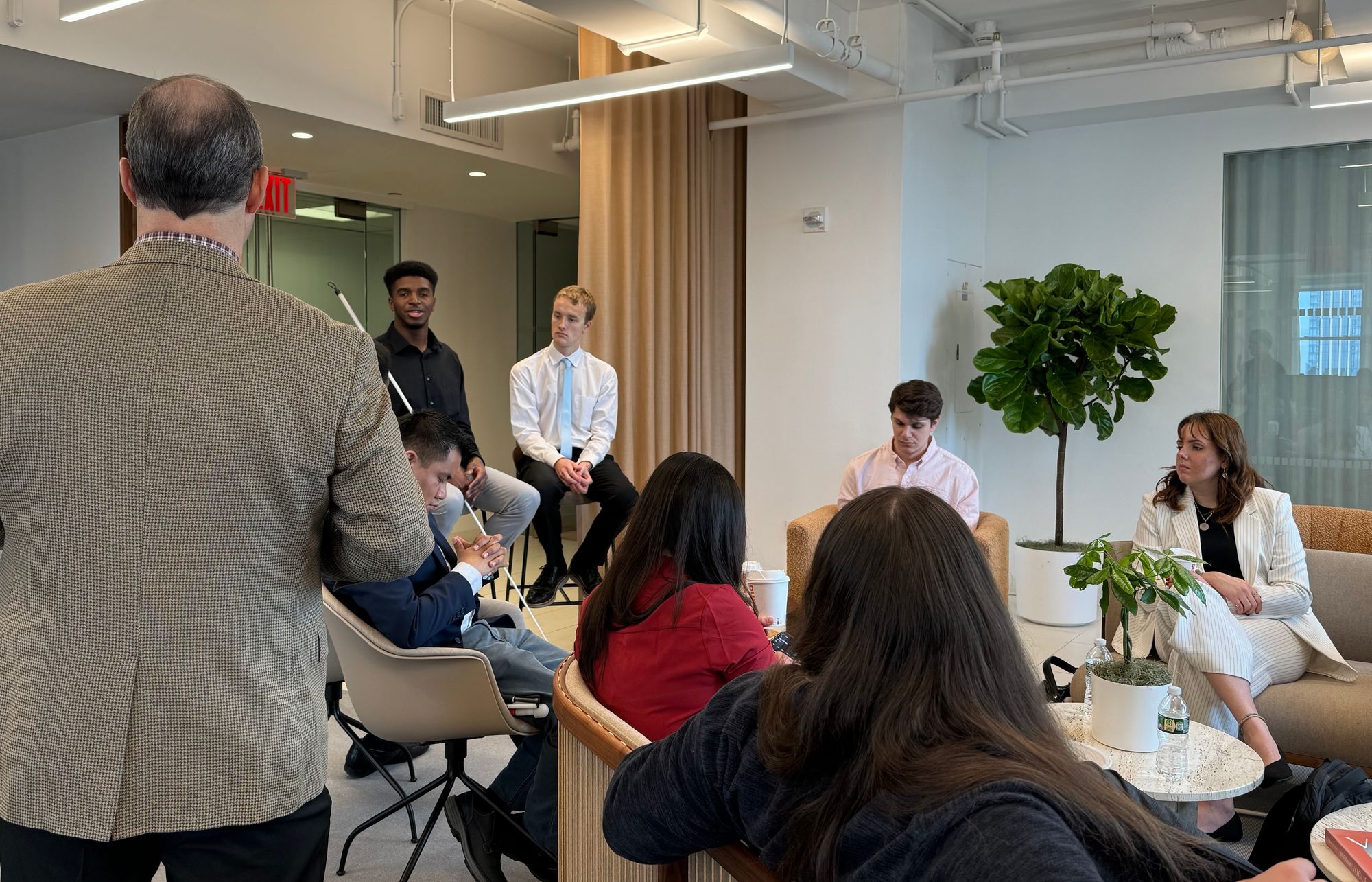 A group of professioanlly dressed people in a room, some holding white canes