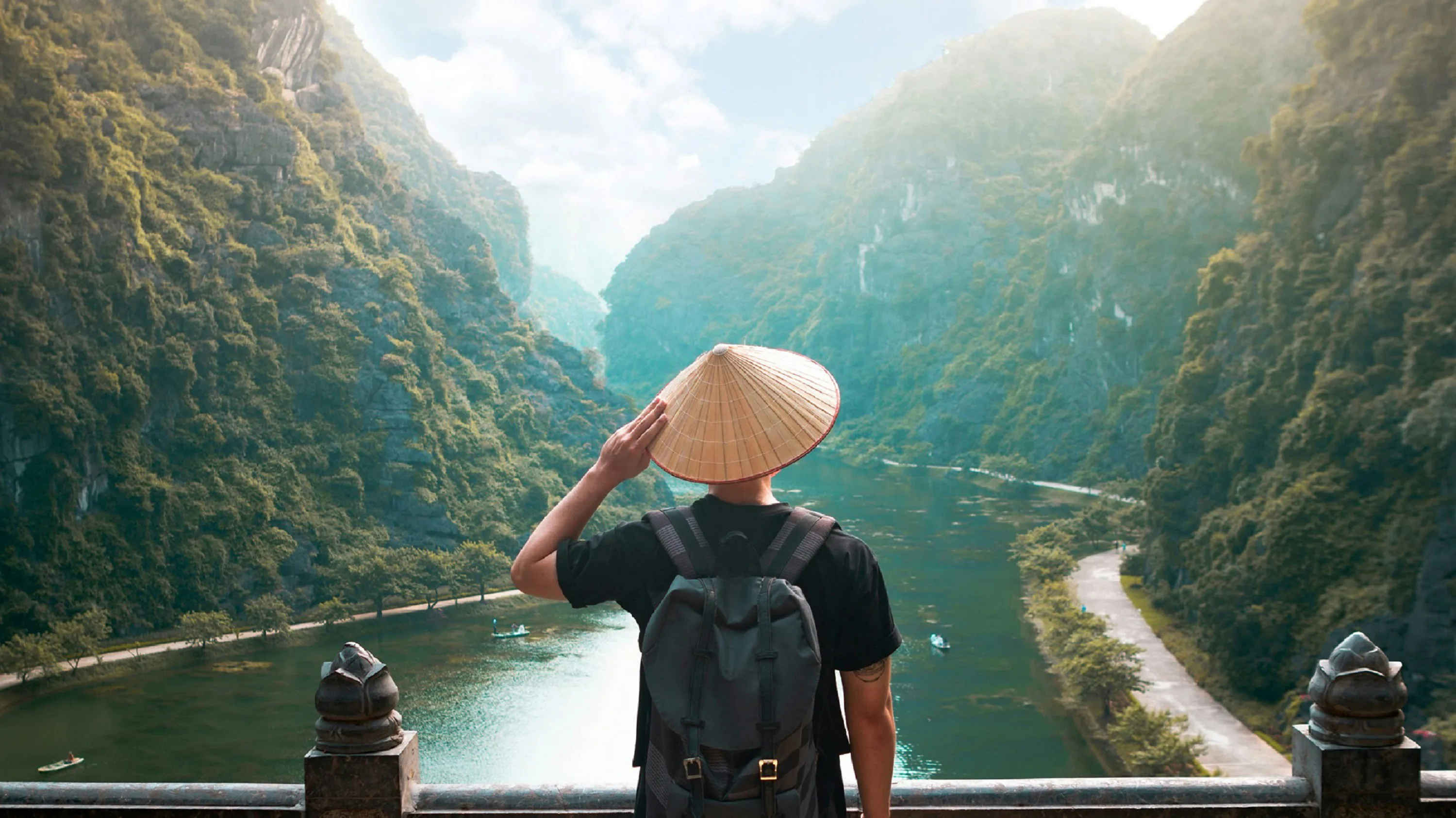 Turist cu palarie vietnameza privind raul in muntii din Ninh Binh, nordul Vietnamului. Foto: Giau Tran / Unsplash