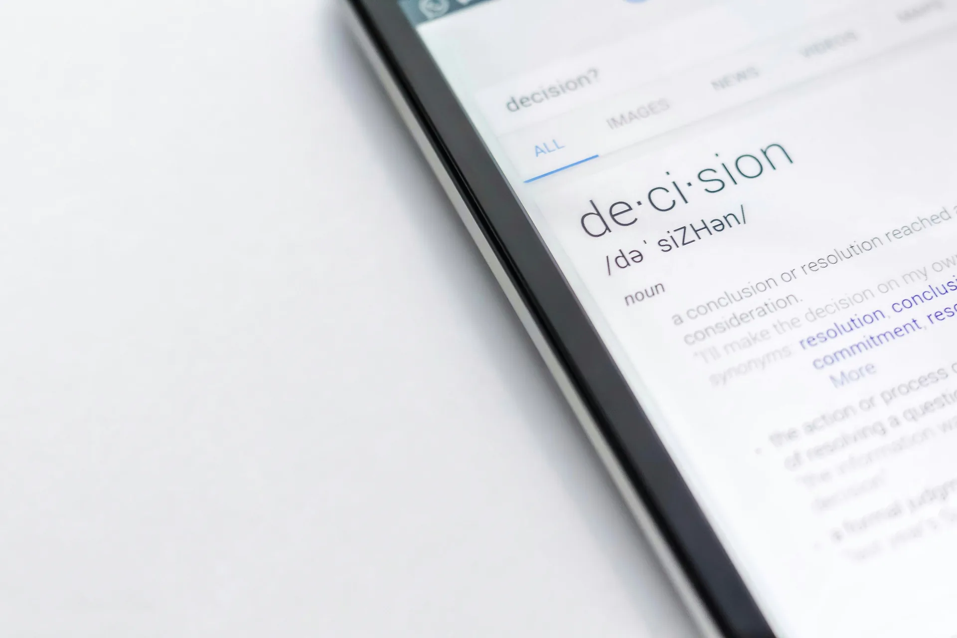 Telefon afisand definitia cuvantului decision pe un ecran de cautare, pe fond alb. Foto: Edho Pratama / Unsplash