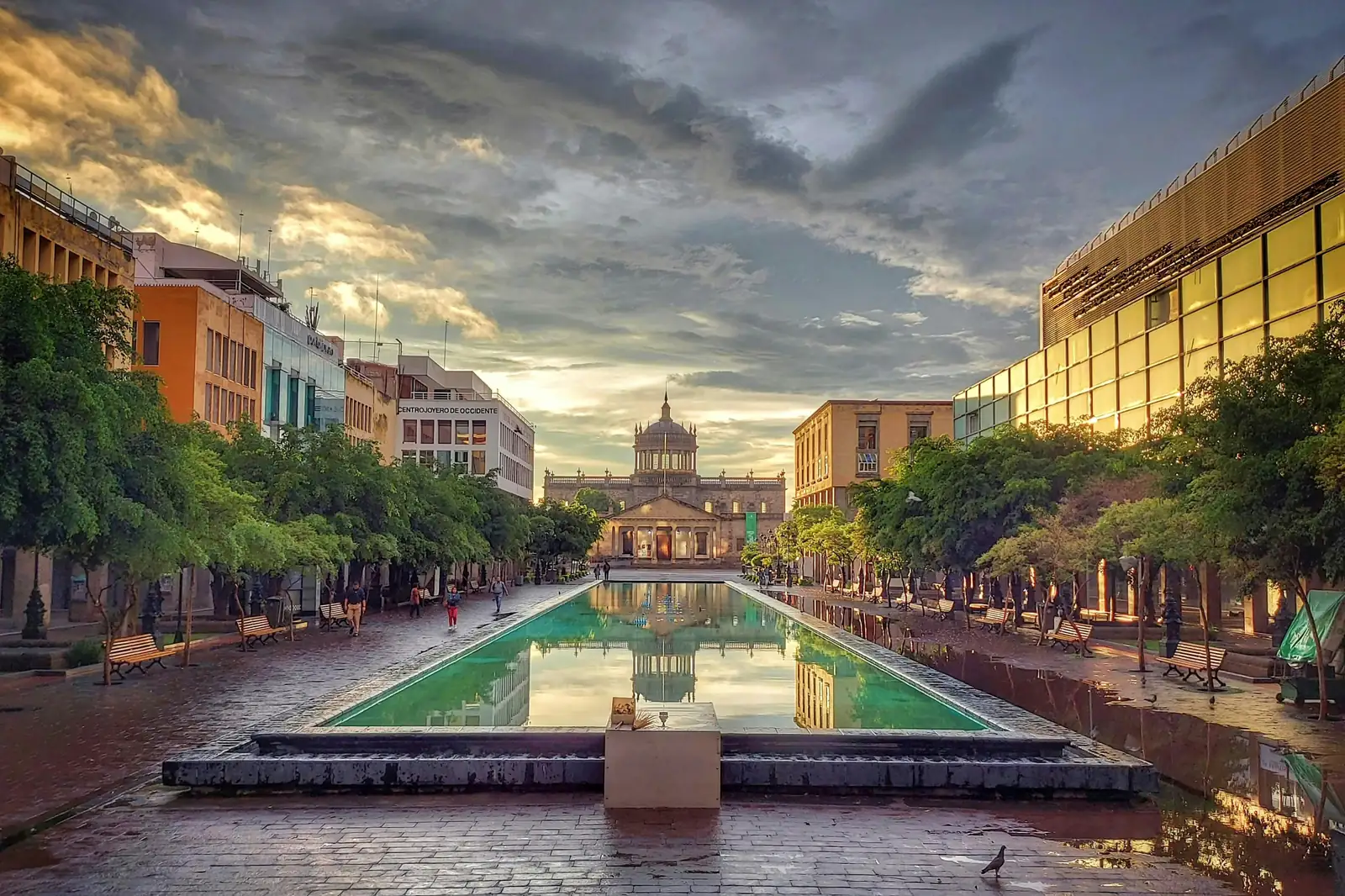 Plaza Tapatía din Guadalajara, cu bazinul lung in care se reflecta Hospicio Cabañas, sub un cer dramatic. Foto: Sergio Rodriguez / Unsplash