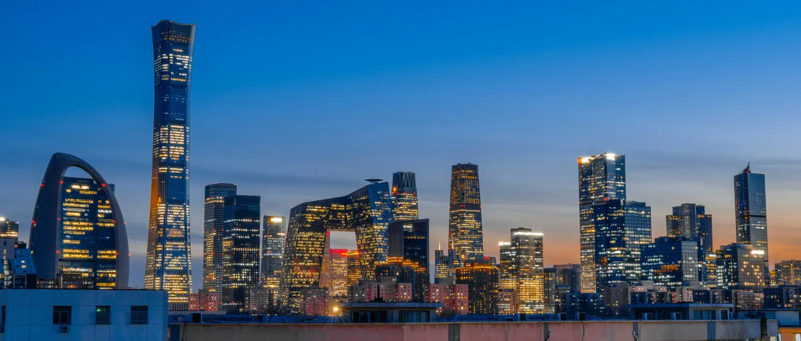 Zgarie-nori din districtul de afaceri din Beijing, cu China Zun si sediul CCTV luminate la amurg. Foto: Yuhan Wang / Unsplash