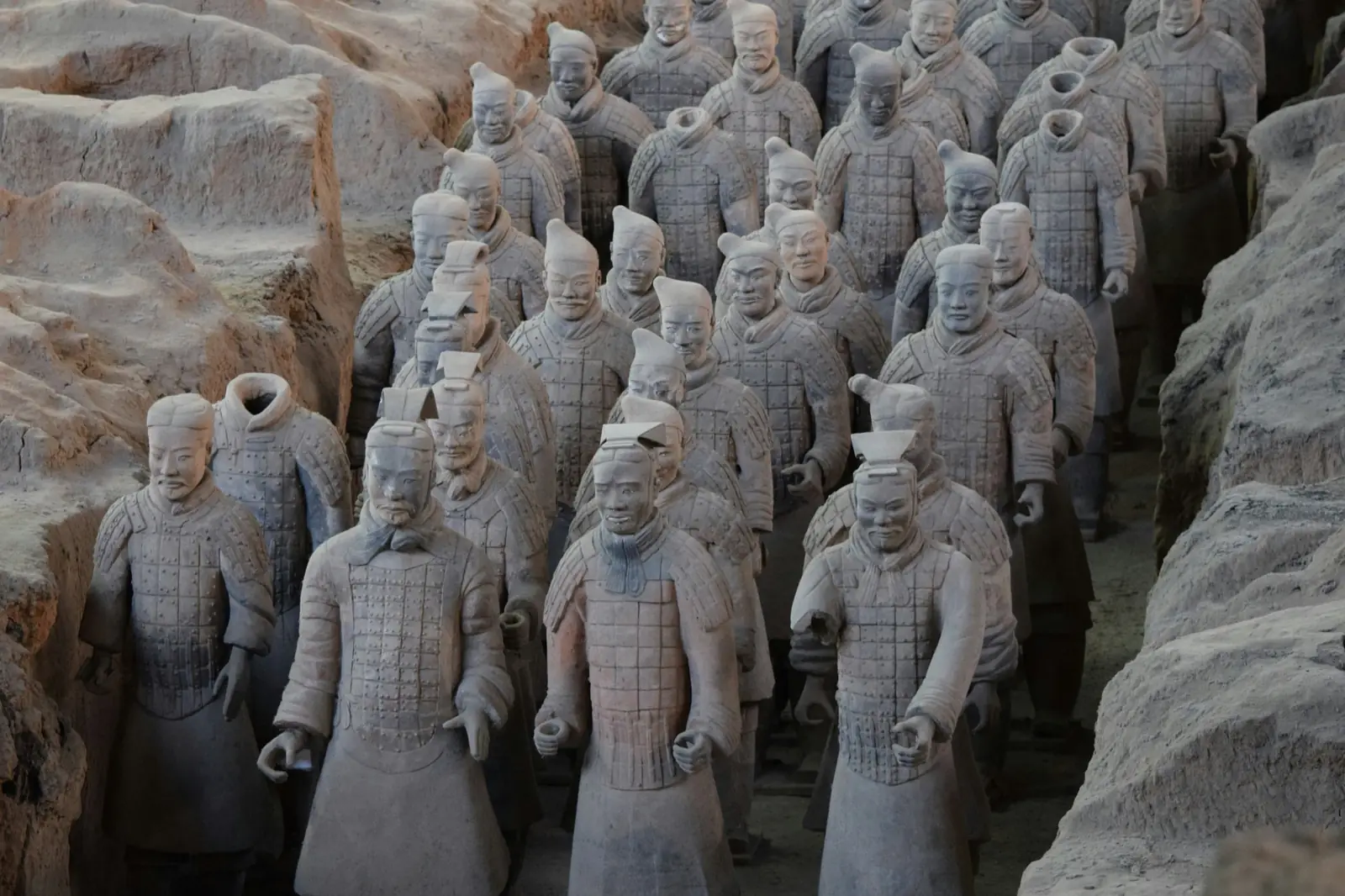 Razboinici din Armata de Teracota aliniati in groapa excavata, cu armuri si fete sculptate in detaliu. Foto: Aaron Greenwood / Unsplash