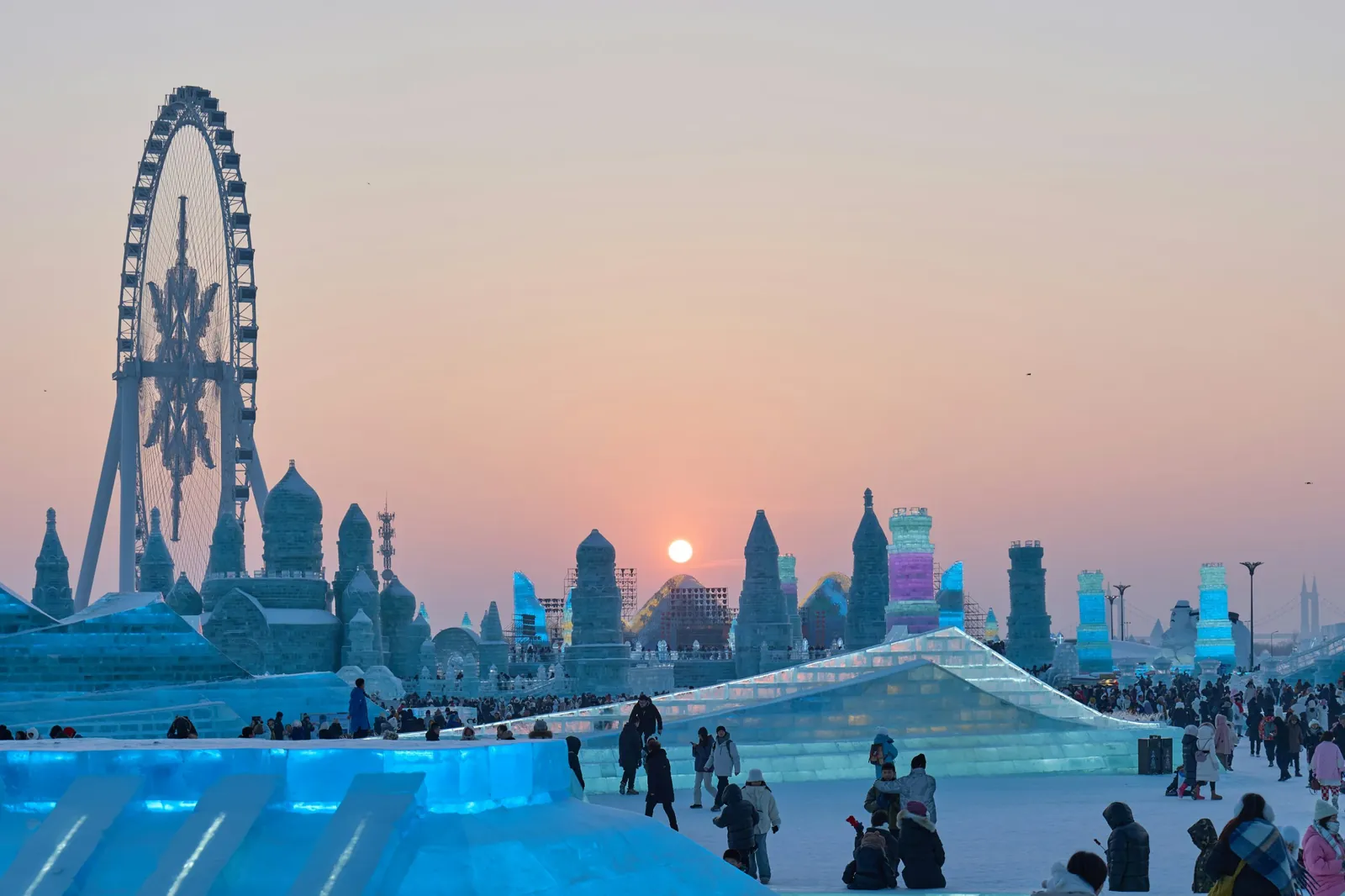 Castele din gheata iluminate si o roata panoramica la Festivalul de Gheata si Zapada din Harbin, cu soarele la orizont. Foto: lin zhaohai / Unsplash
