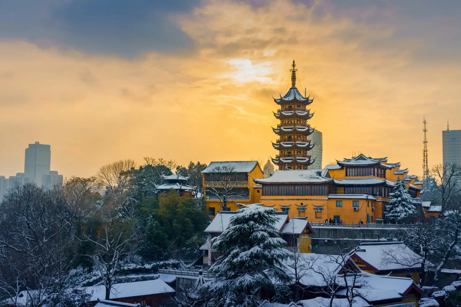Templul Jiming din Nanjing, cu ziduri galbene si pagoda acoperite de zapada, sub un cer auriu de iarna. Foto: Kenneth Yang / Unsplash