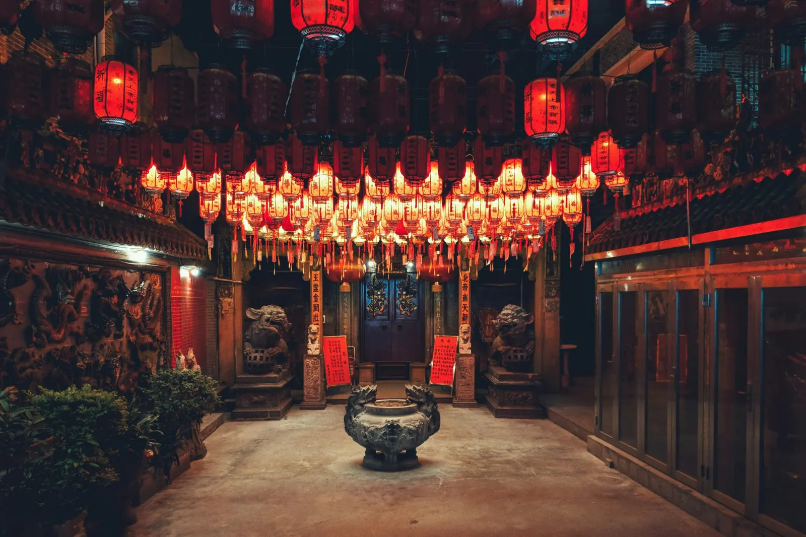 Curte de templu din Baoan, Shenzhen, noaptea, cu sute de lampioane rosii aprinse, lei de piatra si un vas pentru tamaie. Foto: Matze Bob / Unsplash