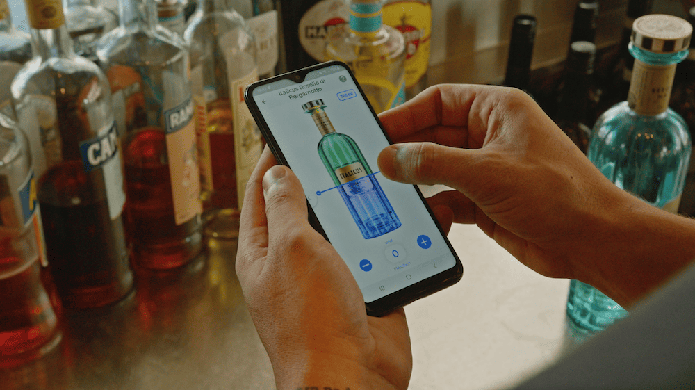 Smartphone zählt angebrochene Spirituosenflasche mit BarBrain Inventursoftware für Bars und Restaurants