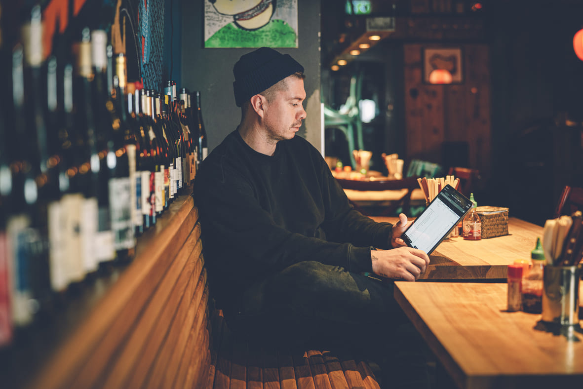 Hospitality professional checks stock levels and inventory list digitally with tablet in a bar.