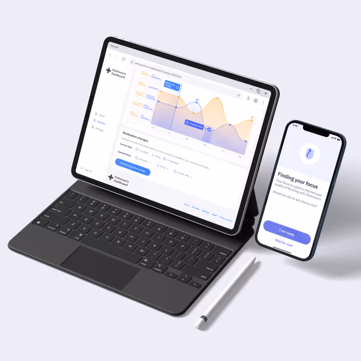 Tablet with keyboard displaying Parkinson's Dashboard medication change graph next to a smartphone showing 'Finding your focus' screen and a white stylus pen.