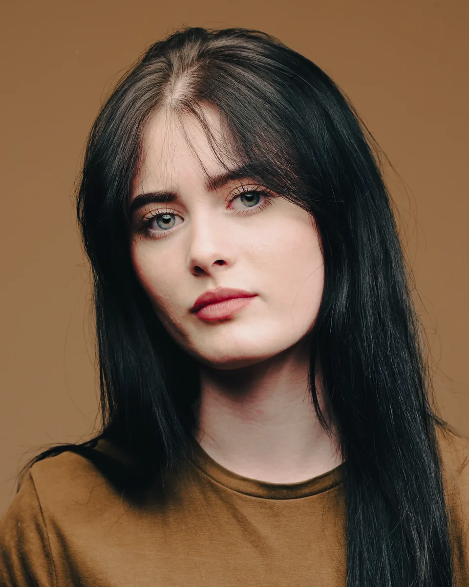 Headshot of a woman with long dark hair in an olive tee on a warm brown backdrop, Dock Street Studio Leeds