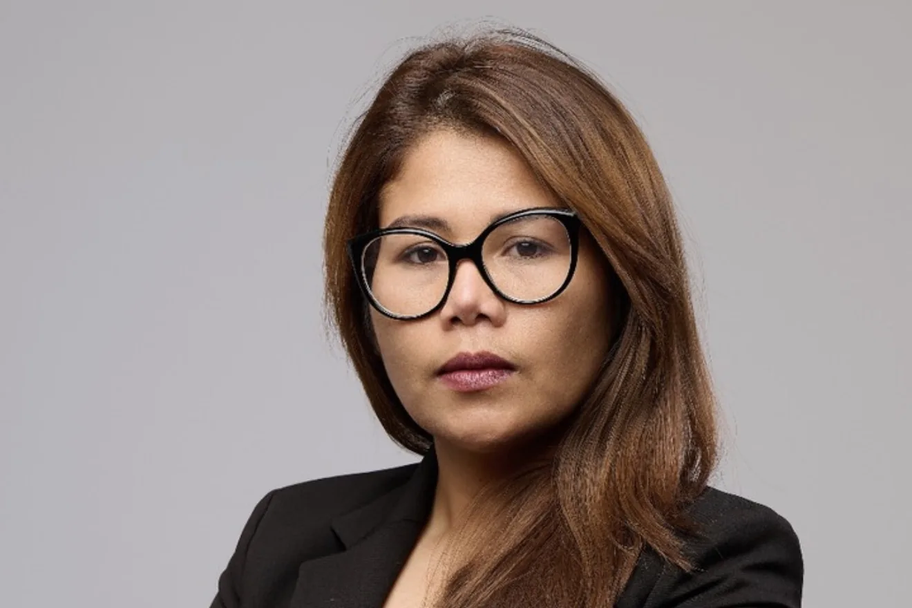 Business headshot of a woman in black-framed glasses and a black blazer on a grey backdrop, Dock Street Studio Leeds