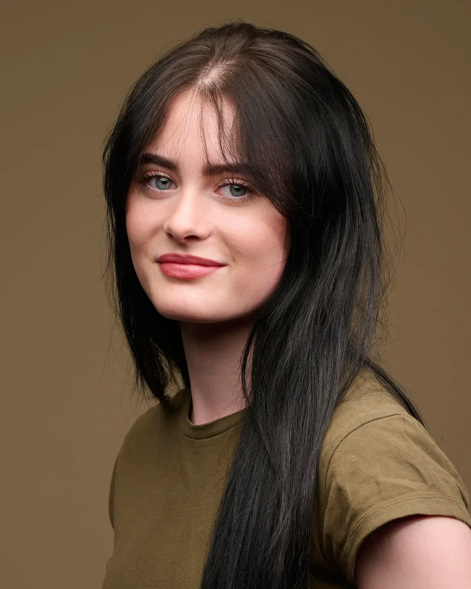 Portrait in a plain olive t-shirt against a warm backdrop, showing how simple clothing photographs well for headshots