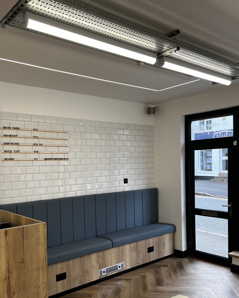 The waiting bench at Barrow Barber Co, with LED lights on cable tray above and sockets set into the bench