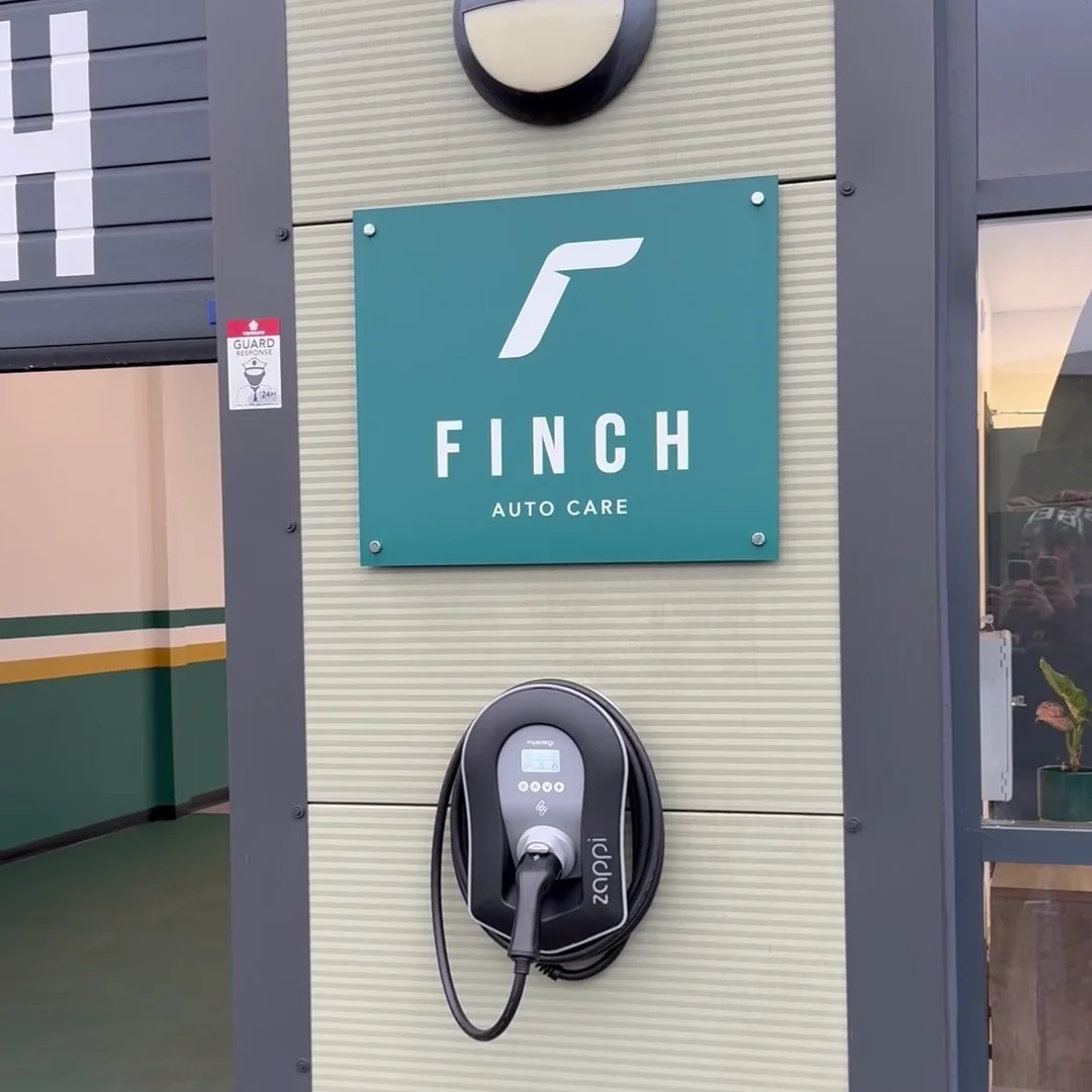 A myenergi Zappi charger on the wall of Finch Auto Care's unit in Wymeswold, under the company sign