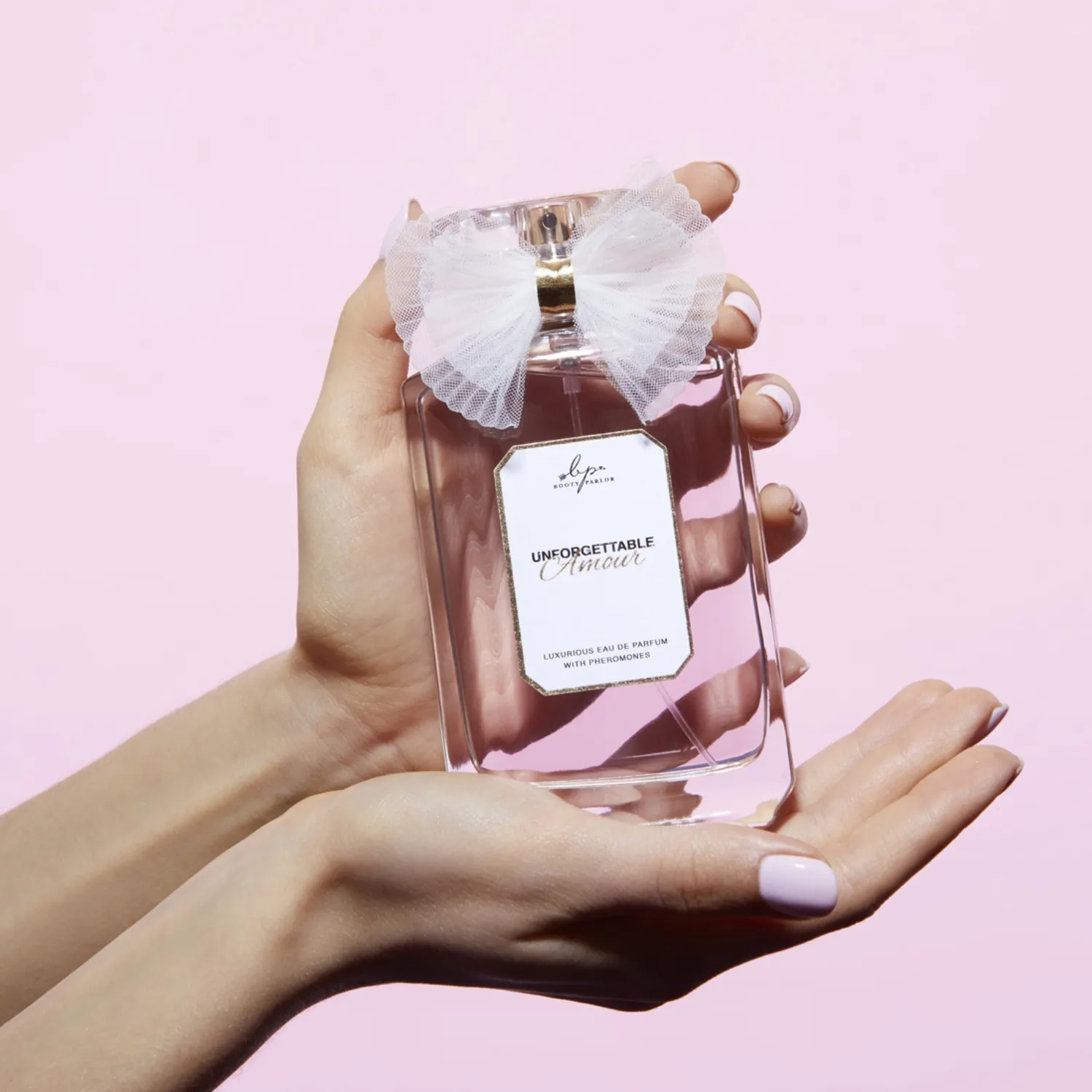 A bottle of perfume with a white bow on top.