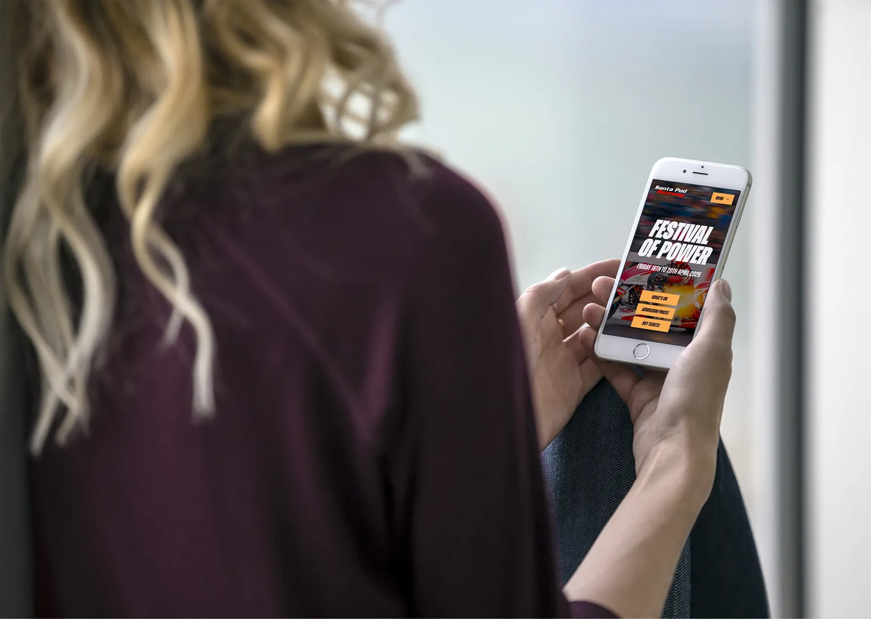 A woman holding a phone with a website about Festivals of Power.