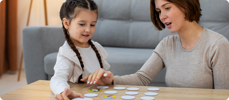 A mother and daughter playing a matching game with flashcards to learn new English words together.