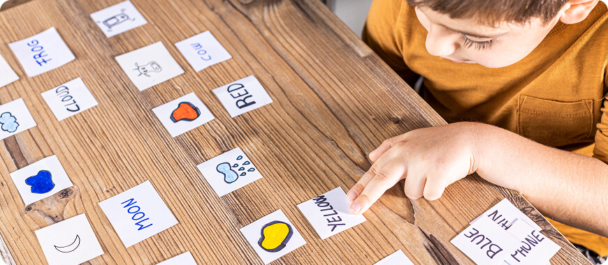 A child pointing at a flashcard labeled 'YELLOW' as part of an engaging vocabulary activity to learn colors in English.