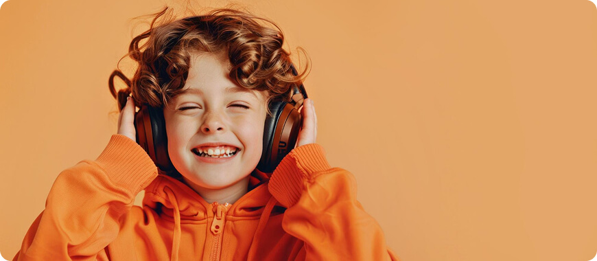 Niño sonriente con auriculares grandes, disfrutando del contenido de audio, ideal para podcasts de aprendizaje de idiomas.
