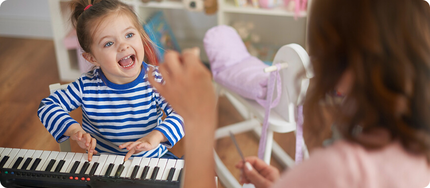 Child playing a keyboard with an adult, using music to learn English vocabulary words in a fun and engaging way.
