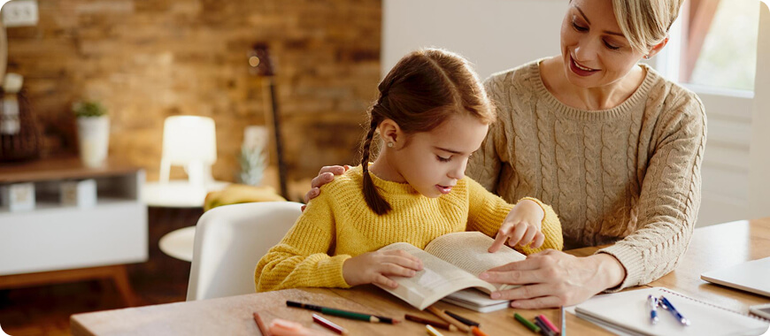 Padre e Hijo Aprendiendo Inglés Juntos – Práctica Divertida del Futuro para Niños en Casa Mamá ayudando a su hija a aprender el futuro en inglés con un libro – ideal para padres que enseñan en casa