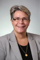 An older woman with short grey hair and glasses smiling.