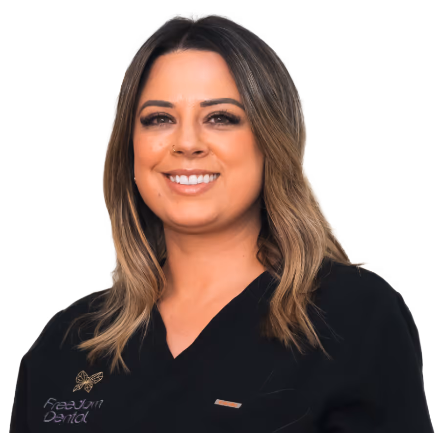 Smiling woman with shoulder-length hair wearing a black Freedom Dental uniform.