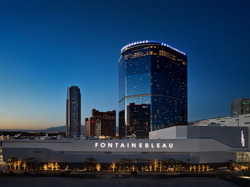 Evening view of the Fontainebleau hotel with its illuminated modern glass tower and exterior signage.