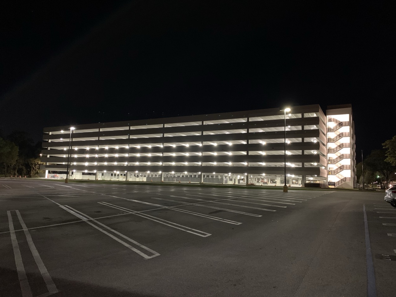 Indoor parking lot with multiple trucks and cars parked under concrete ceiling lights.