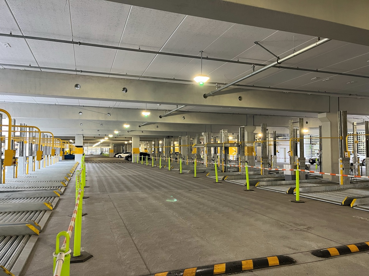Empty indoor parking garage level with ceiling lights and green occupancy indicator lights.