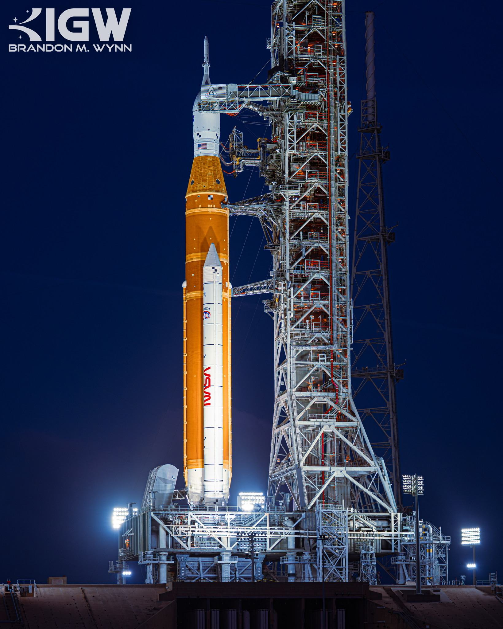 NASA's Space Launch System on its mobile launcher at night, floodlit, Orion at the top of the stack.