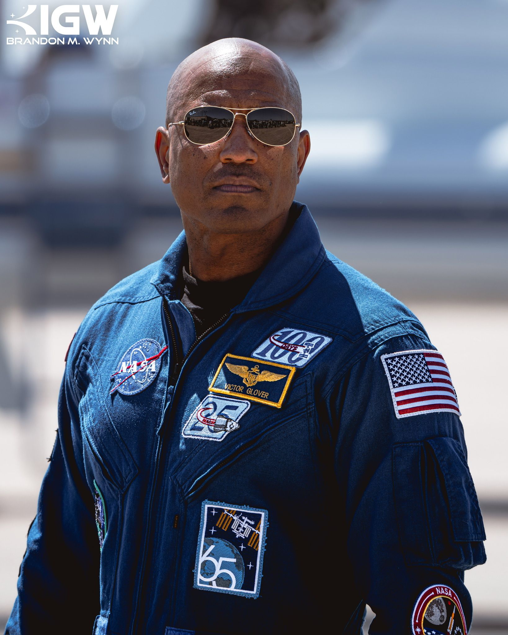 Victor Glover in a blue NASA flight suit, wearing sunglasses.