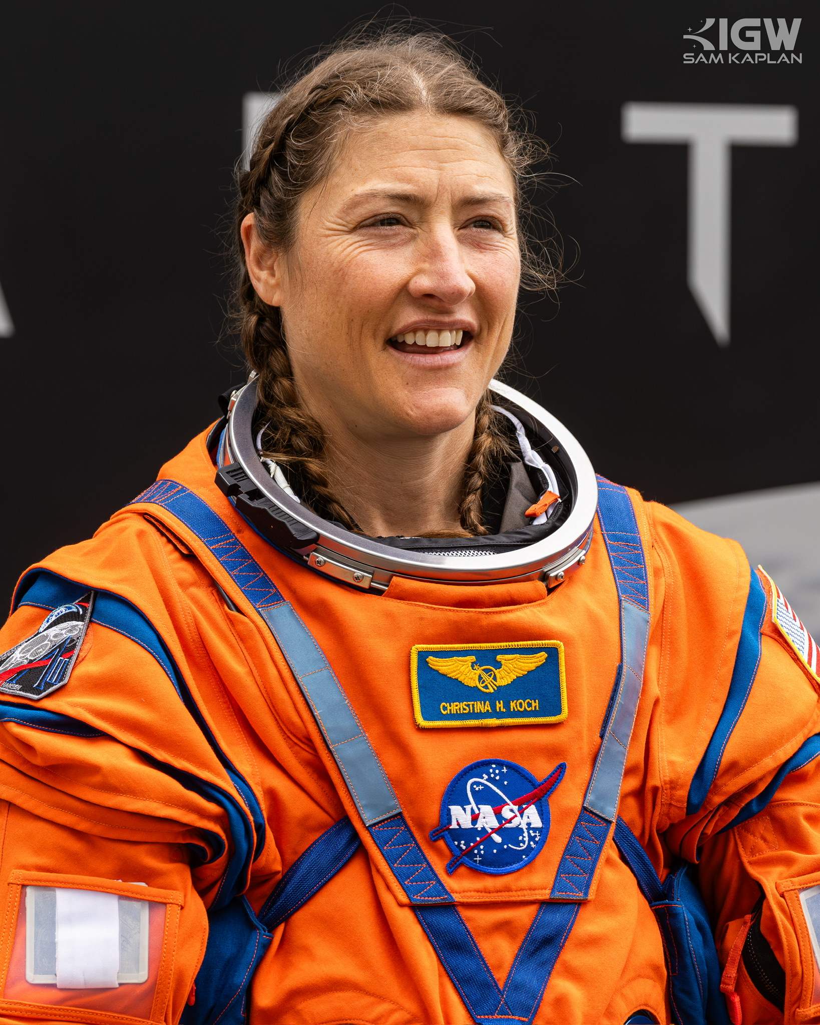 Christina Koch in the orange launch and entry suit, helmet ring open, smiling.