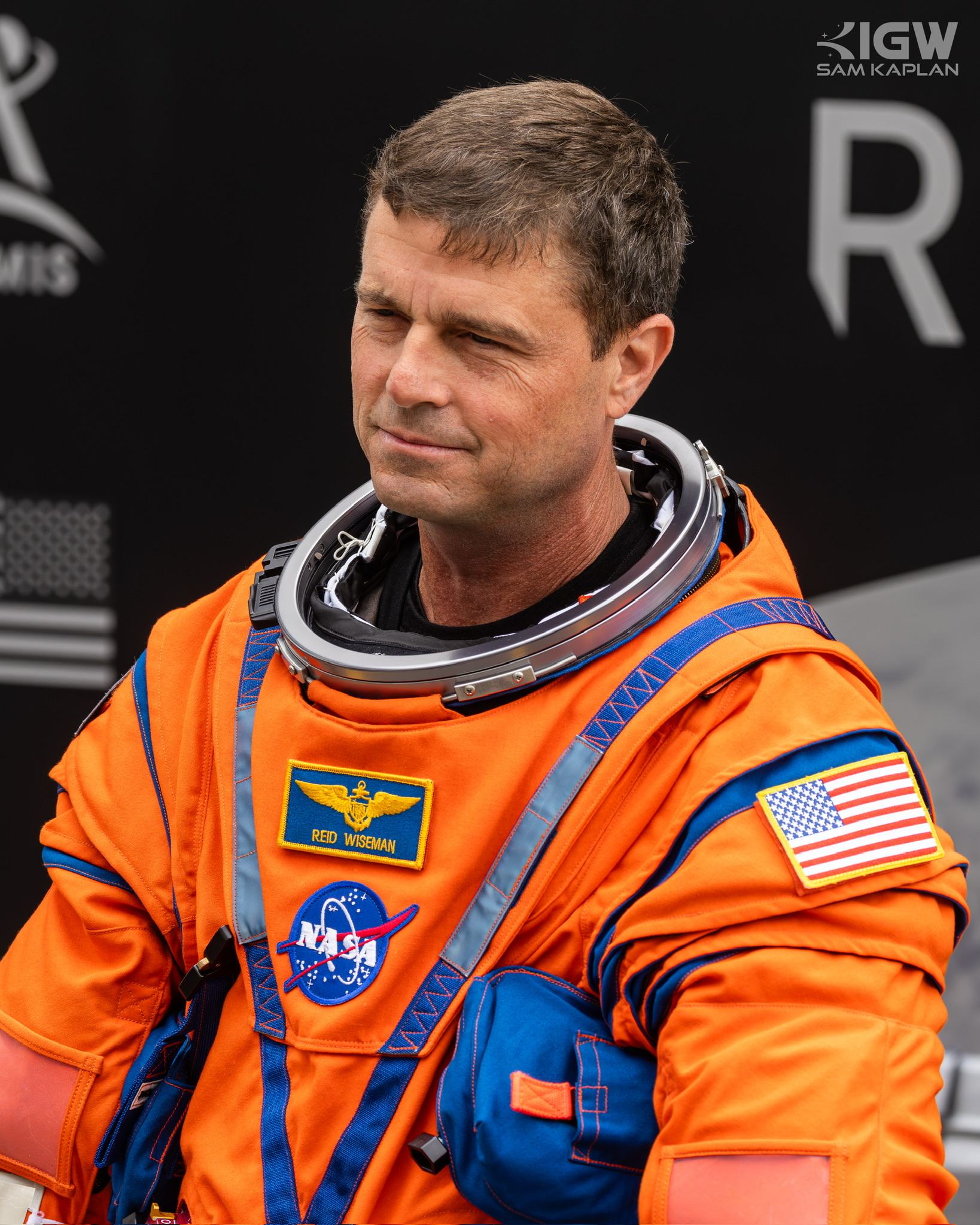 Reid Wiseman in the orange launch and entry suit, looking to one side.