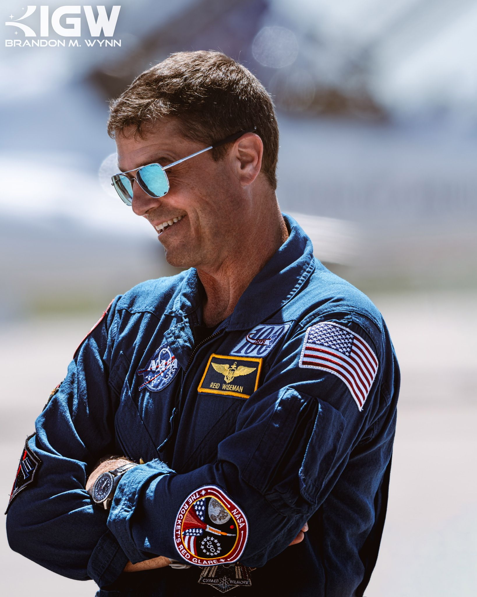 Reid Wiseman in a blue NASA flight suit, smiling in sunglasses.