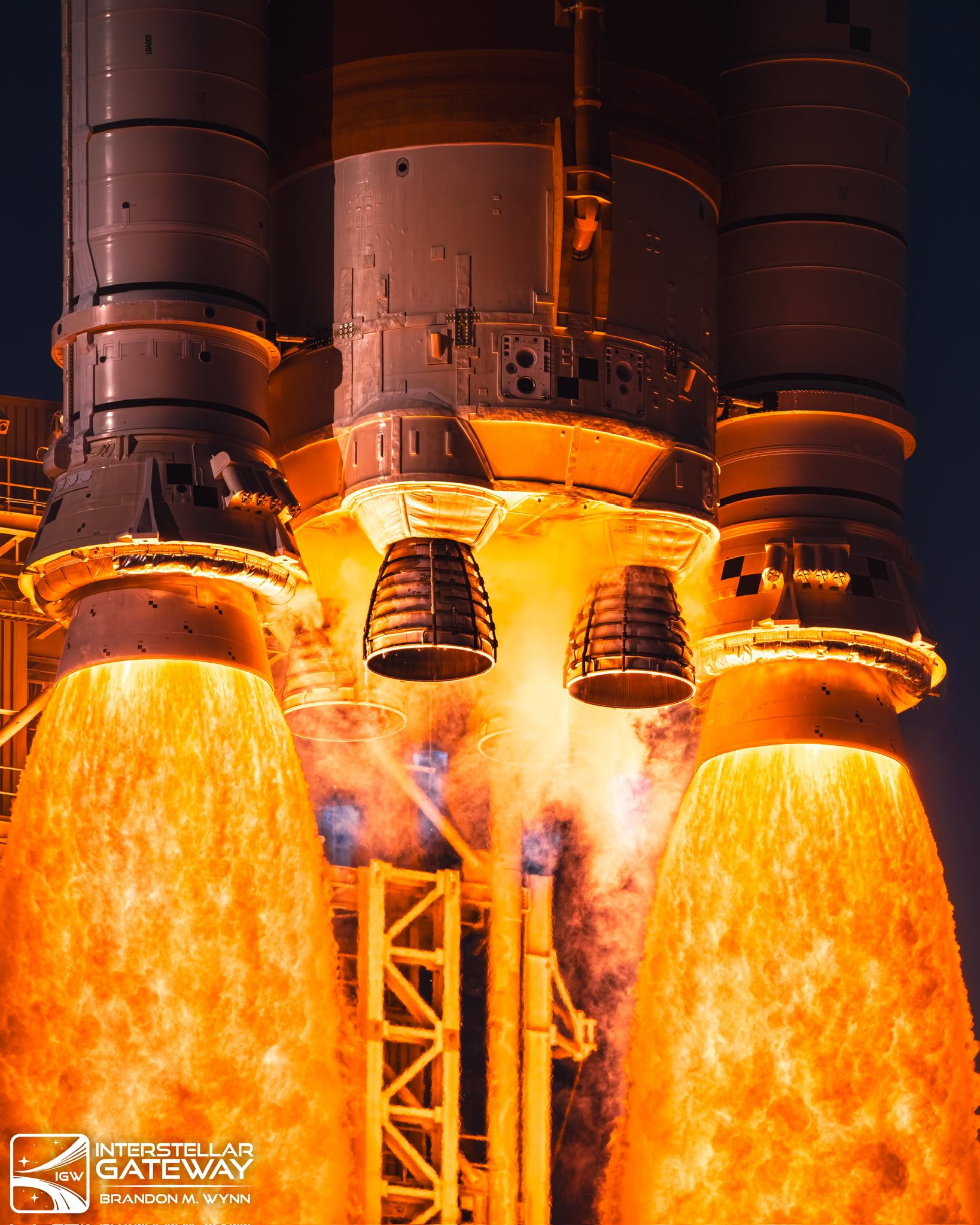 The Space Launch System's core stage engines and booster nozzles at ignition, flame filling the frame.