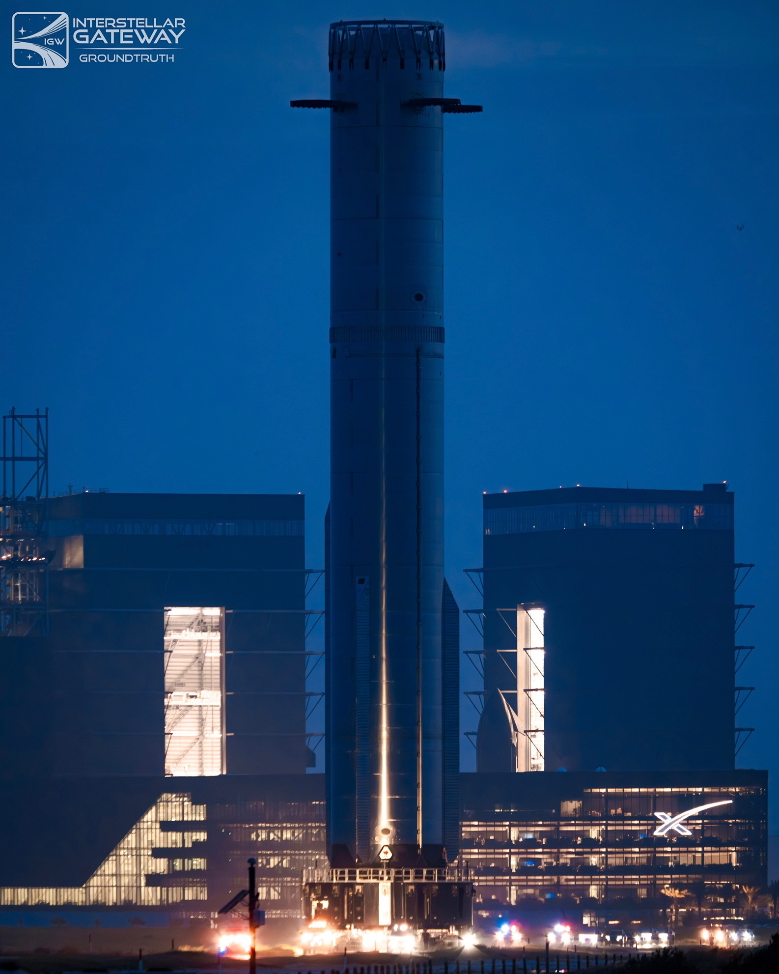 Starship stacked on the launch mount at Starbase at night, the tower floodlit.