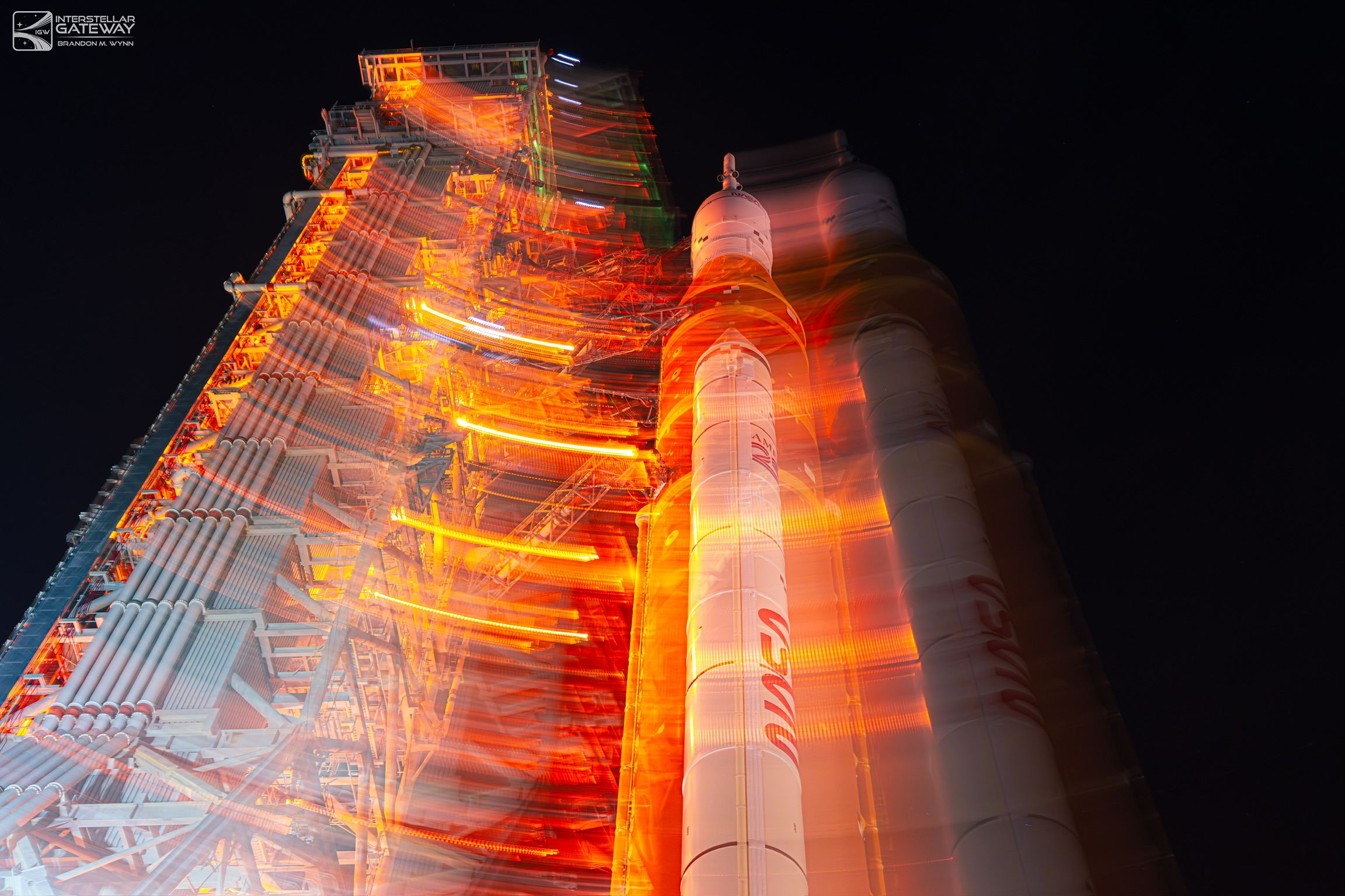 The Space Launch System on its mobile launcher at night in a long exposure, streaked with light.