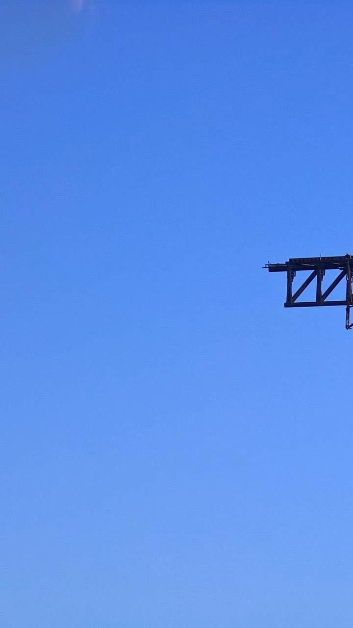 A dark steel lattice arm juts in from the right edge of the frame against an otherwise empty, clear blue sky.