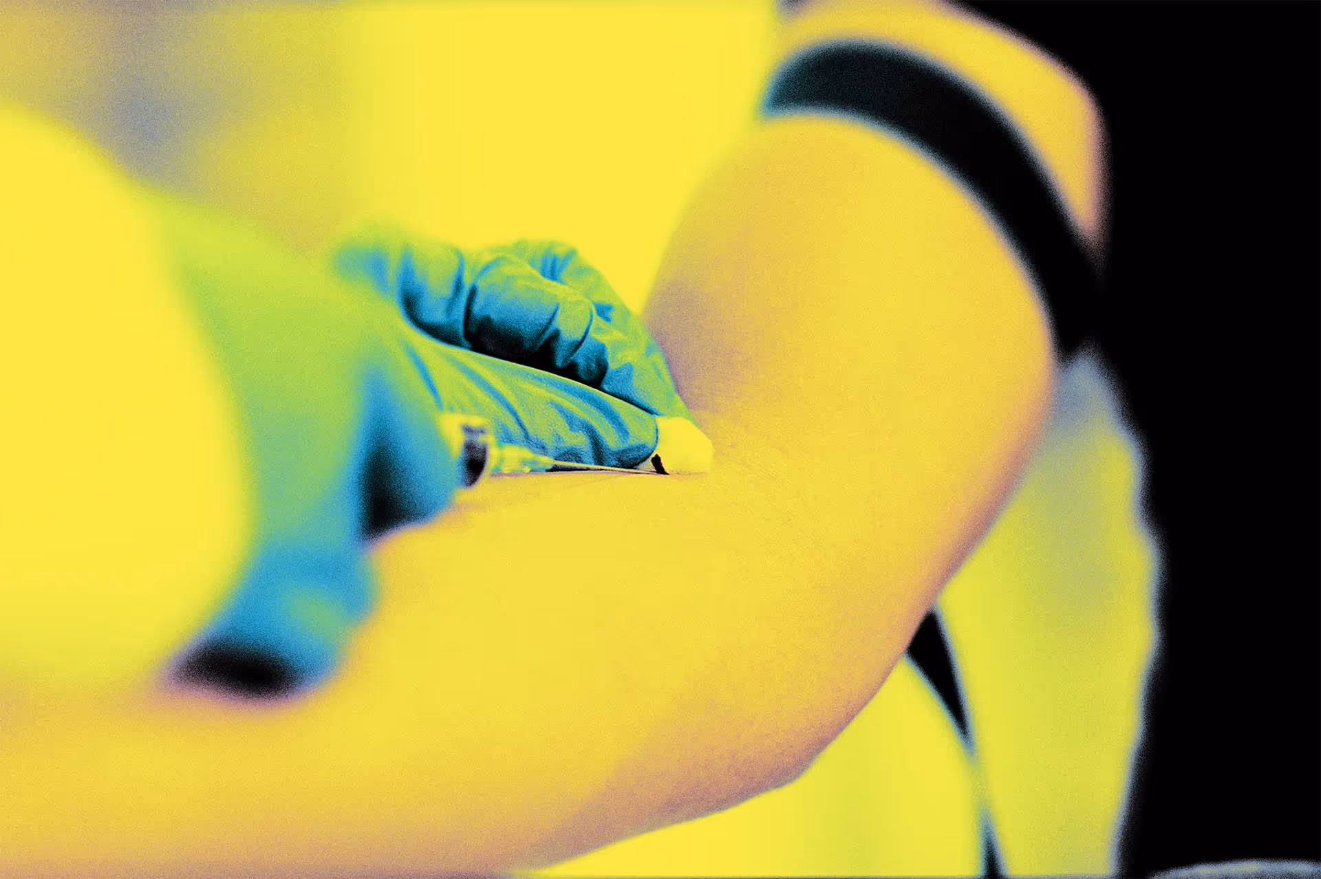 Close-up of a medical professional wearing gloves drawing blood from a patient's arm with a syringe.