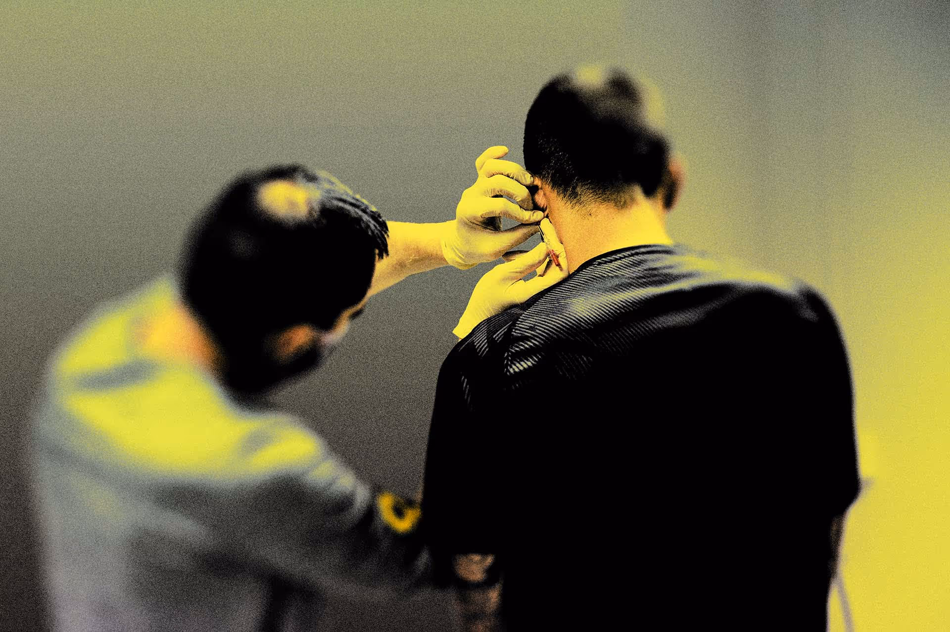 Person wearing gloves handing a thin object near the neck of another person.