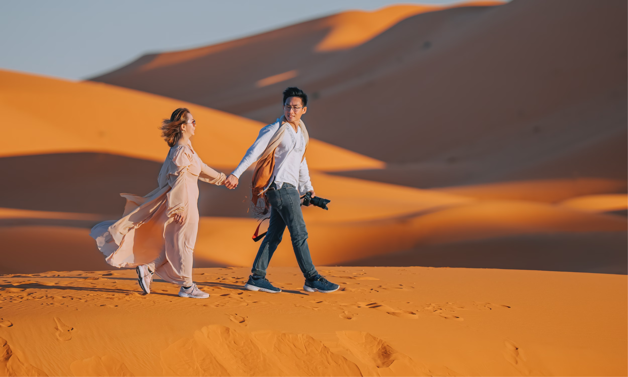 Couple walking hand in hand across Namibia’s sand dunes.