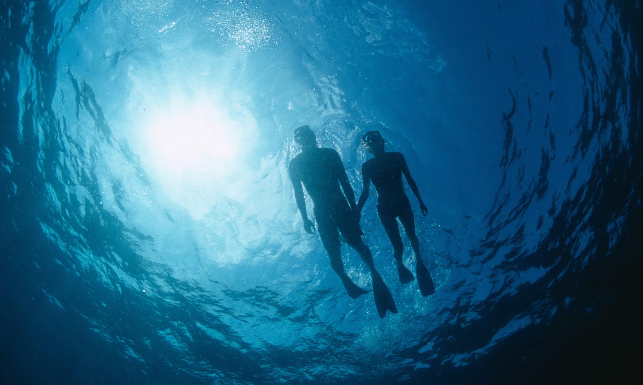 Honeymoon couple snorkeling in the crystal-clear waters of the Cook Islands.