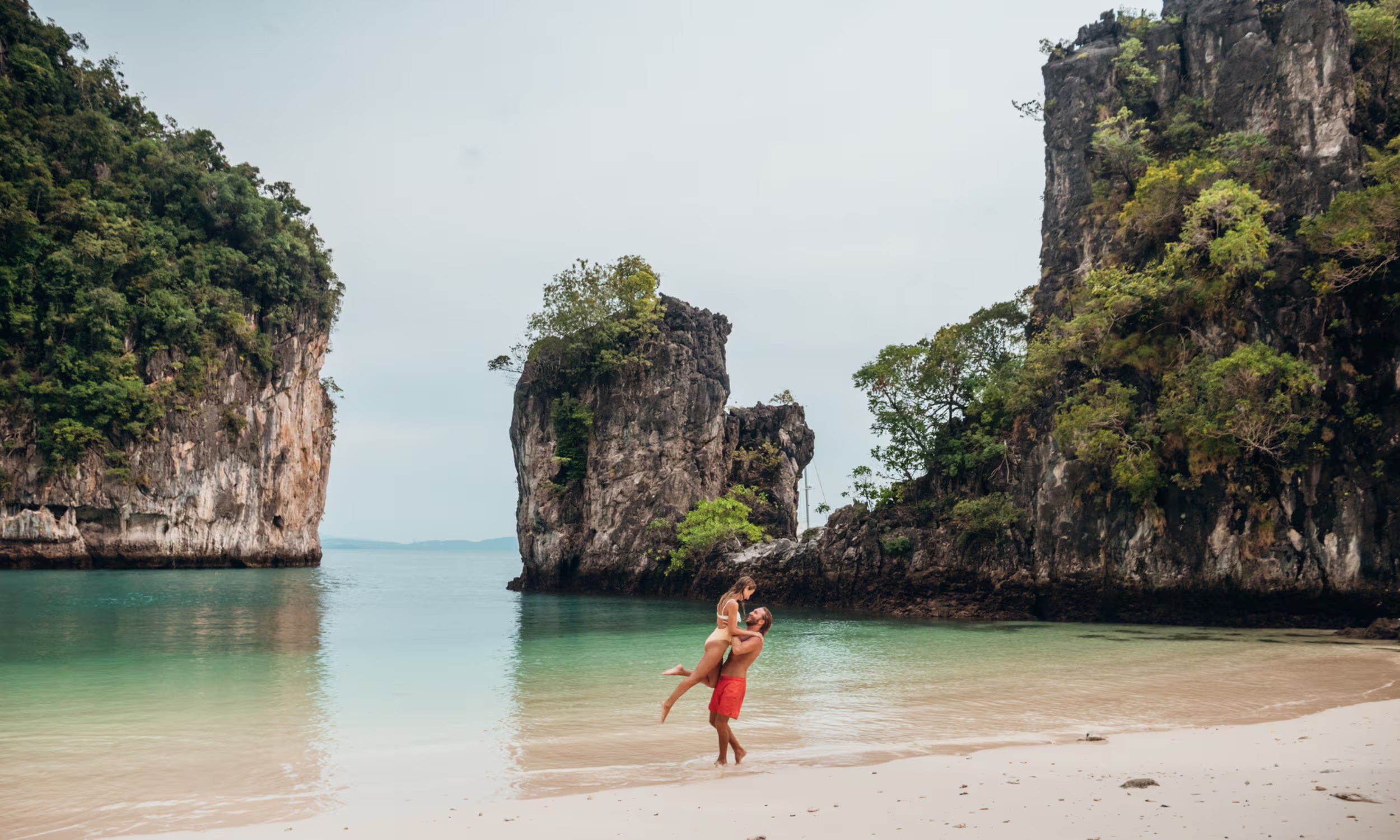 Casal numa praia paradisíaca na Tailândia durante uma viagem romântica de lua de mel.