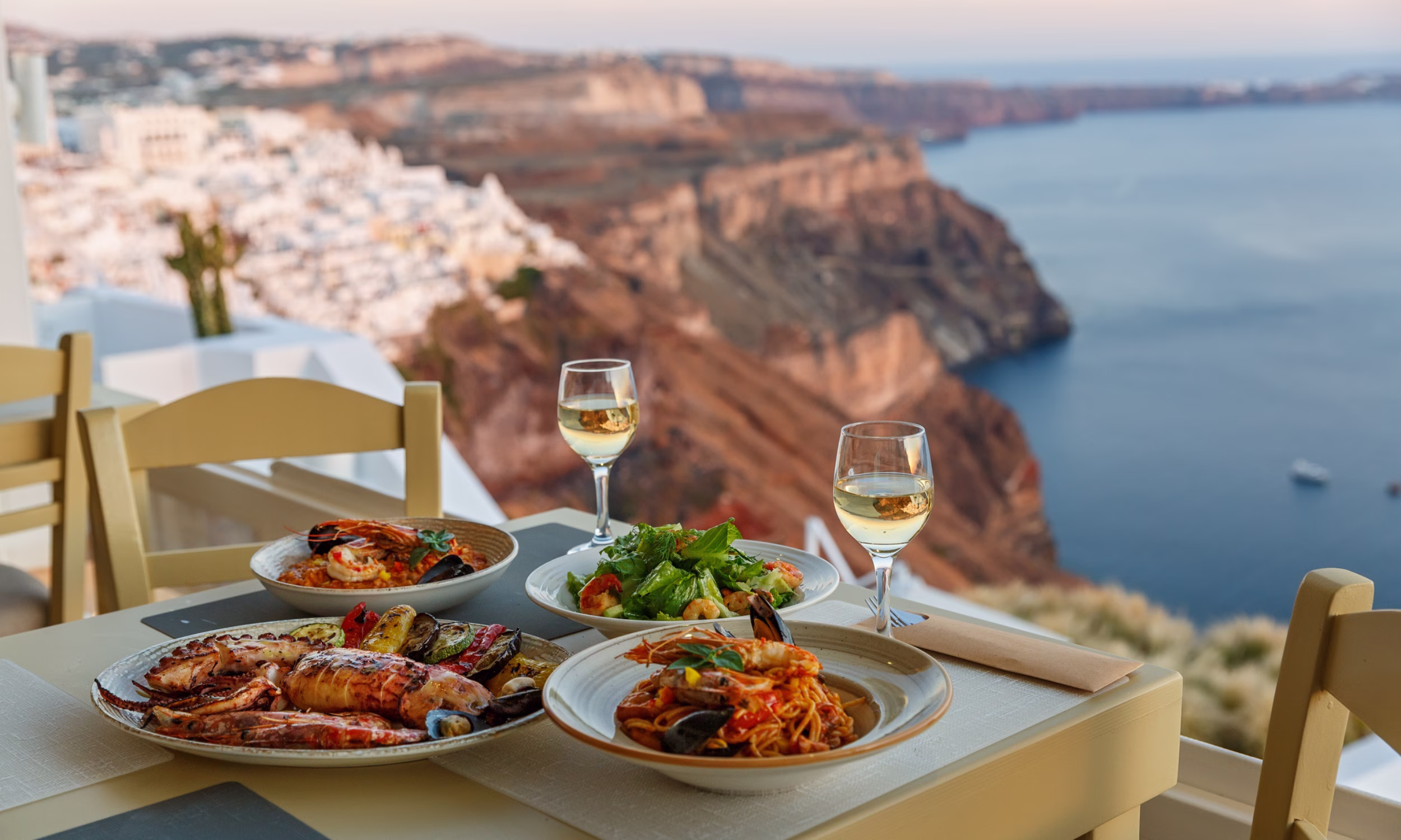Romantic Greek dinner with white wine and sea view in Santorini. 